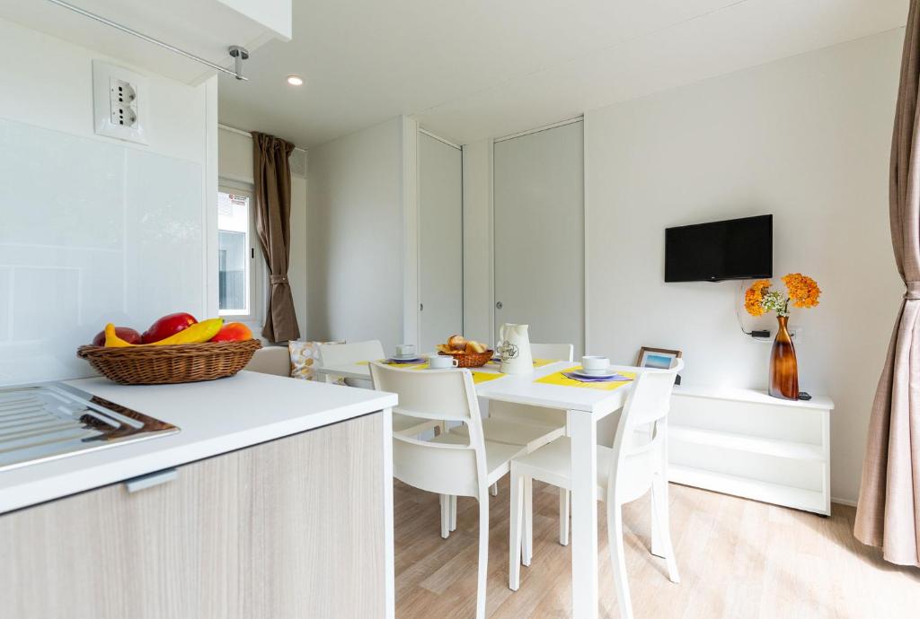 una cucina e una sala da pranzo con tavolo e sedie bianchi di Camping Marelago a Caorle