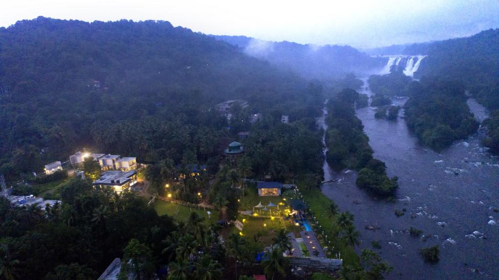 einen Luftblick auf einen Fluss mit einem Wasserfall in der Unterkunft Casa Rio Resorts Athirappilly in Athirappilly