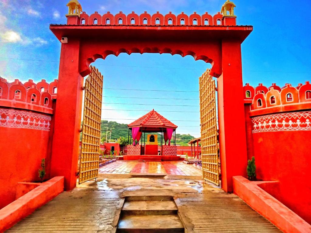 um arco com um edifício vermelho ao fundo em Santkrupa Villa Resort em Nakhtrana