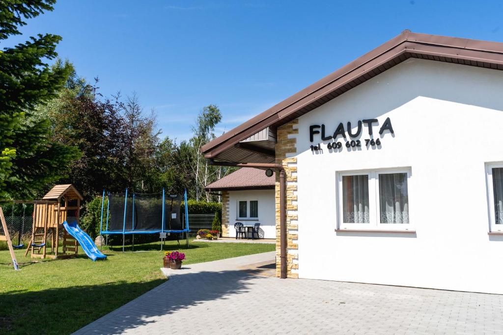 a white building with a playground in a yard at Flauta Apartamenty Rodzinne in Mielenko