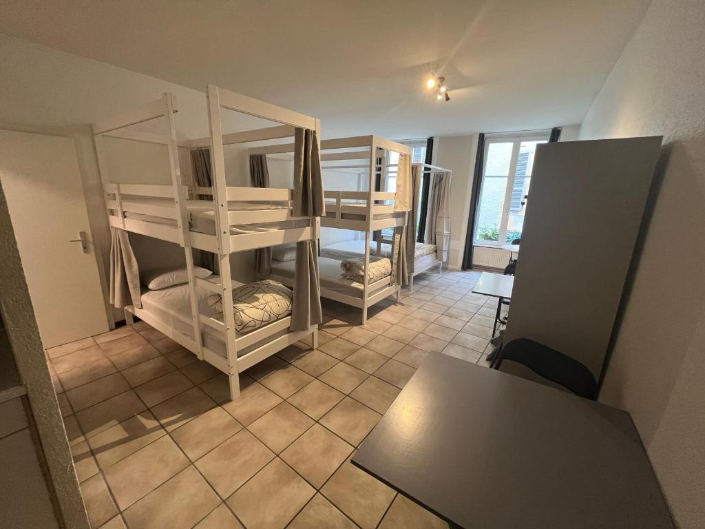 a dorm room with bunk beds and a table at Auberge de jeunesse hyper centre de Neuchâtel in Neuchâtel