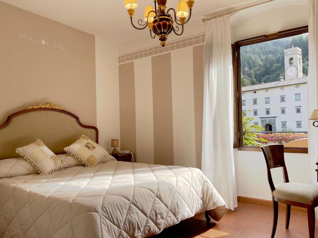 um quarto com uma cama, uma janela e uma cadeira em Hotel Rifugio la Foresta em Vallombrosa