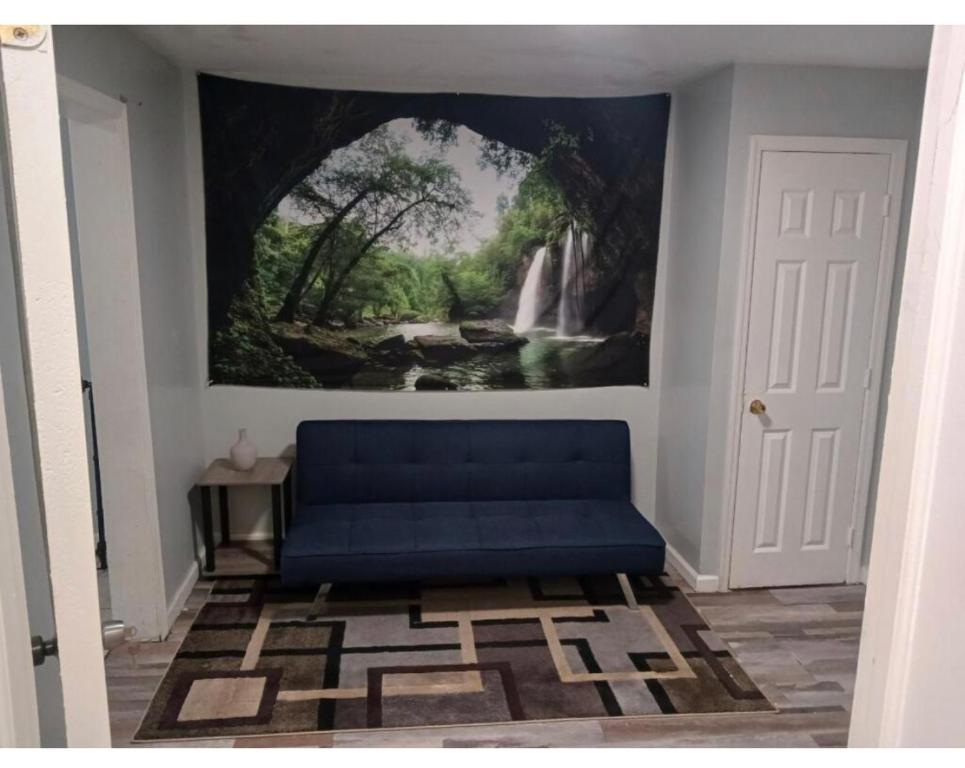 um sofá azul num quarto com uma pintura na parede em Cozy 2 bedrooms and a Yard em Brooklyn