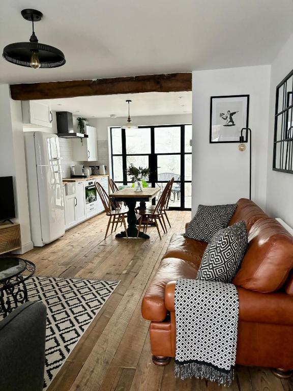 Hotel Stunning 3 bedroom & 2 bathroom cottage with patio, a living room with a leather couch and a table at Stunning 3 bedroom & 2 bathroom cottage with patio in Brighton & Hove