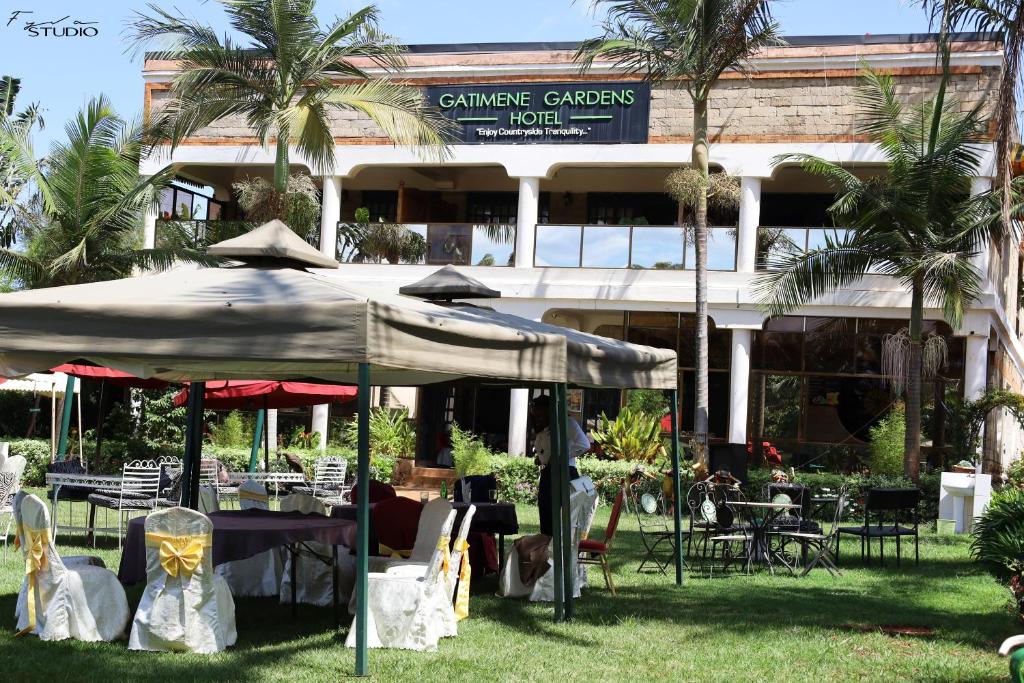 a restaurant with tables and chairs in front of a building at Gatimene Gardens Hotel in Meru