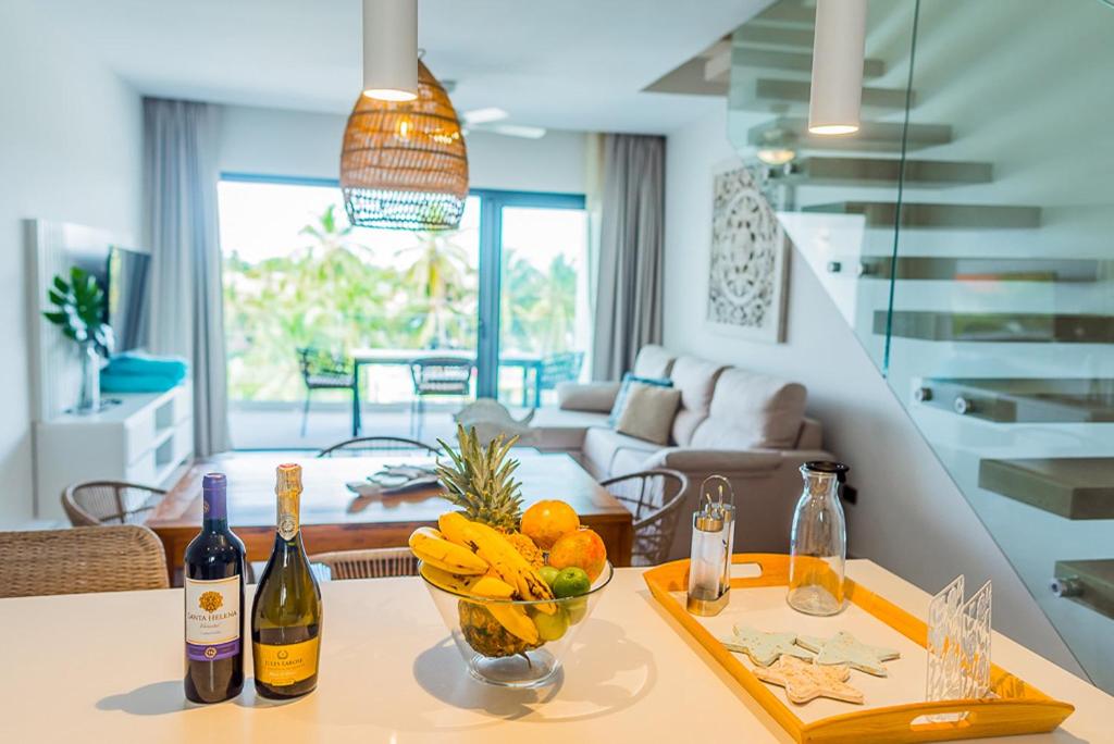 a kitchen with a table with a bowl of fruit and wine bottles at Stylish and spacious penthouse with Bbq and picuzi in Punta Cana