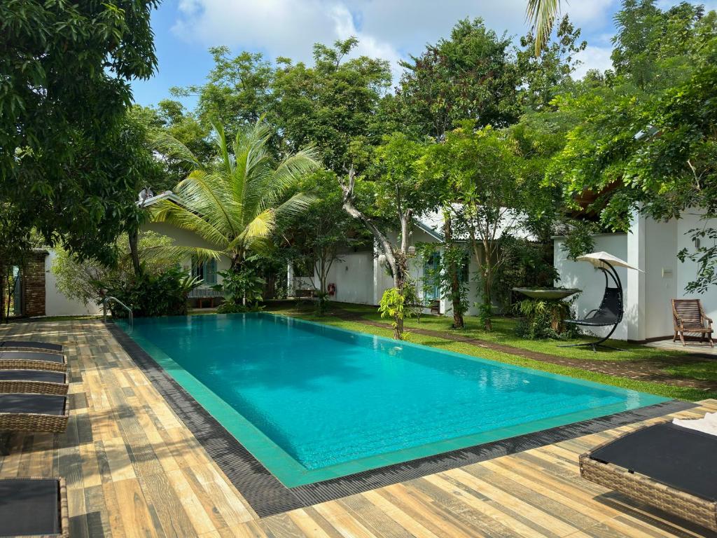 a swimming pool in front of a house with trees at Kandalama Lodge in Dambulla