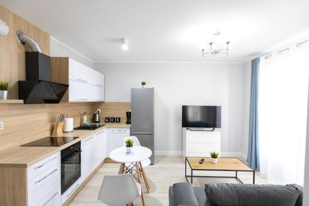 uma cozinha e sala de estar com armários brancos e uma mesa em Apartament 8B Wały Chrobrego Szczecin em Szczecin