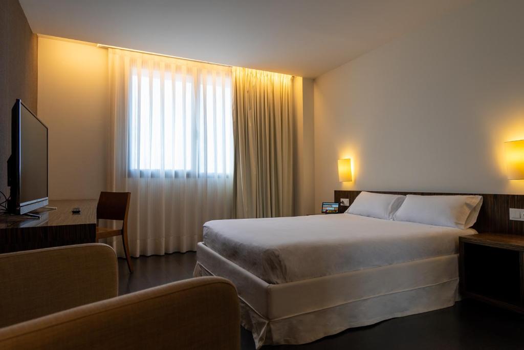 アーロにあるKyriad Direct ETH Riojaのベッドとテレビが備わるホテルルームです。