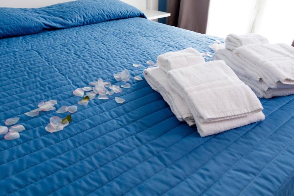 ein blaues Bett mit Handtüchern und Blumen darauf in der Unterkunft Casavacanzefranca - 12 in Terrasini