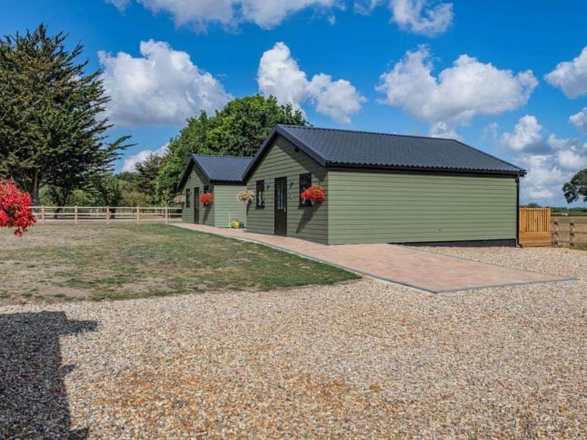 a large green building with a garage at Cabin Hideaways in Mattishall