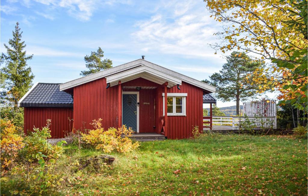 a red shed in a grassy field with trees at Beautiful Home In ros With Kitchen in Fagerstrand
