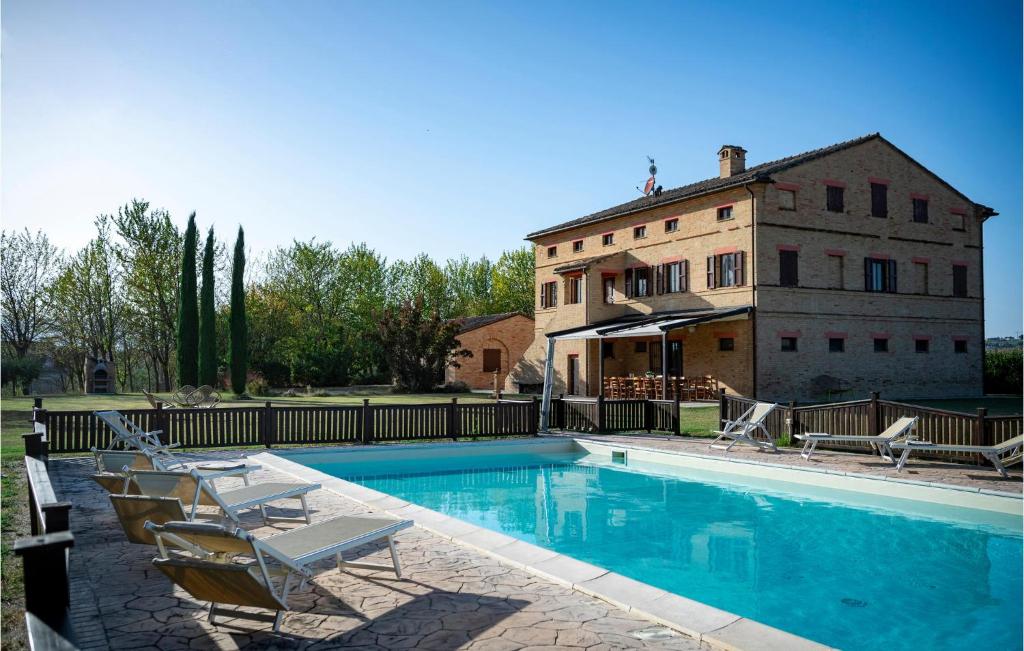 a house with a swimming pool with chairs and a building at 6 Bedroom Awesome Home In Treia in Appignano