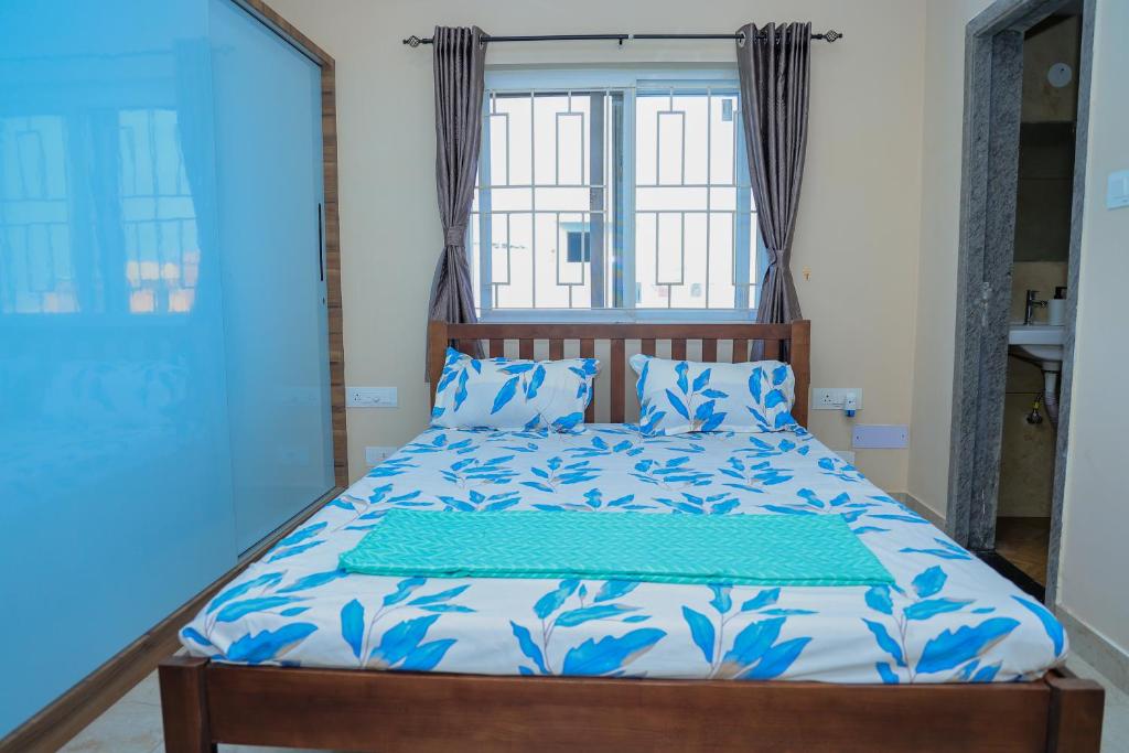 a bedroom with a bed with blue and white sheets and a window at Swayamkrushi 4th floor in Hyderabad