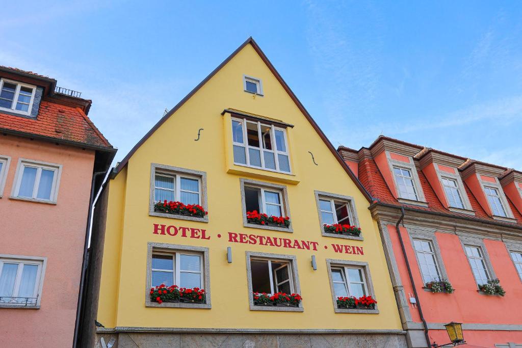 a yellow building with flowers in the windows at Laurentius Boutique-Hotel & Restaurant in Weikersheim