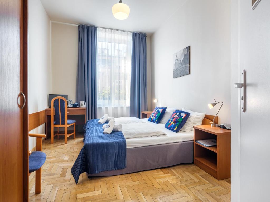 1 dormitorio con 1 cama con manta azul y escritorio en Kosmopolita Rooms en Cracovia