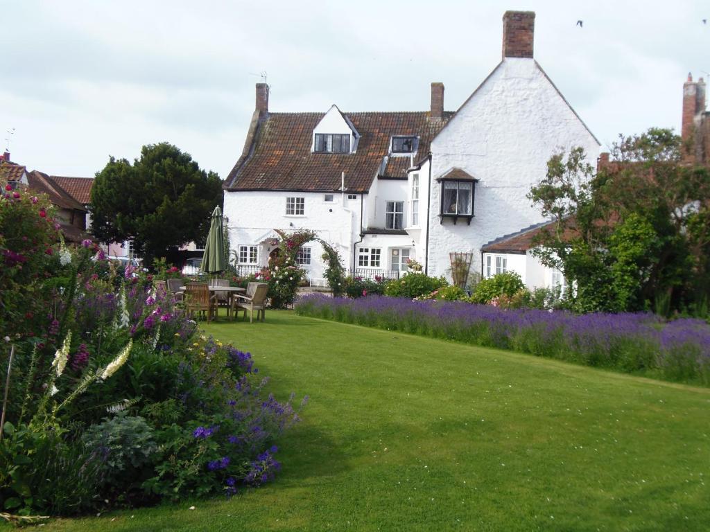 a white house with a garden with purple flowers at The Old House in Nether Stowey