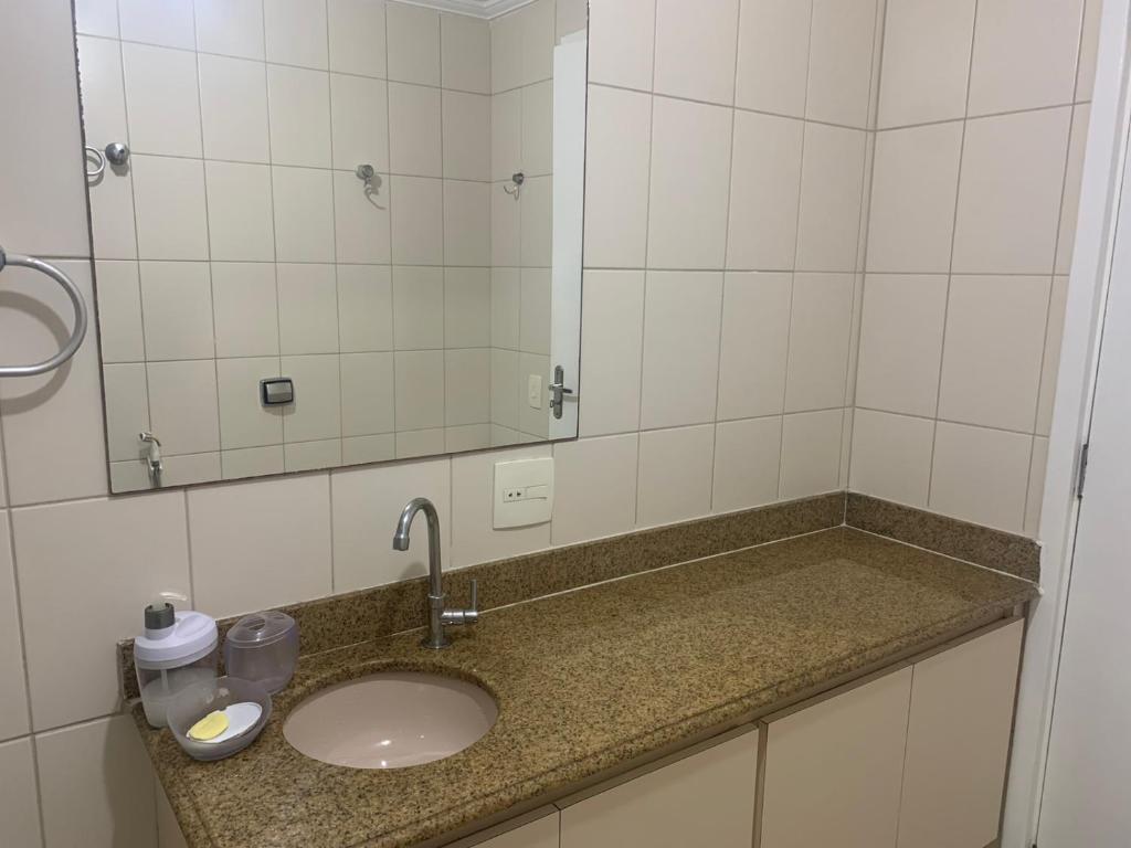 a bathroom counter with a sink and a mirror at Apartamento Astúrias a menos de 50m da praia in Guarujá