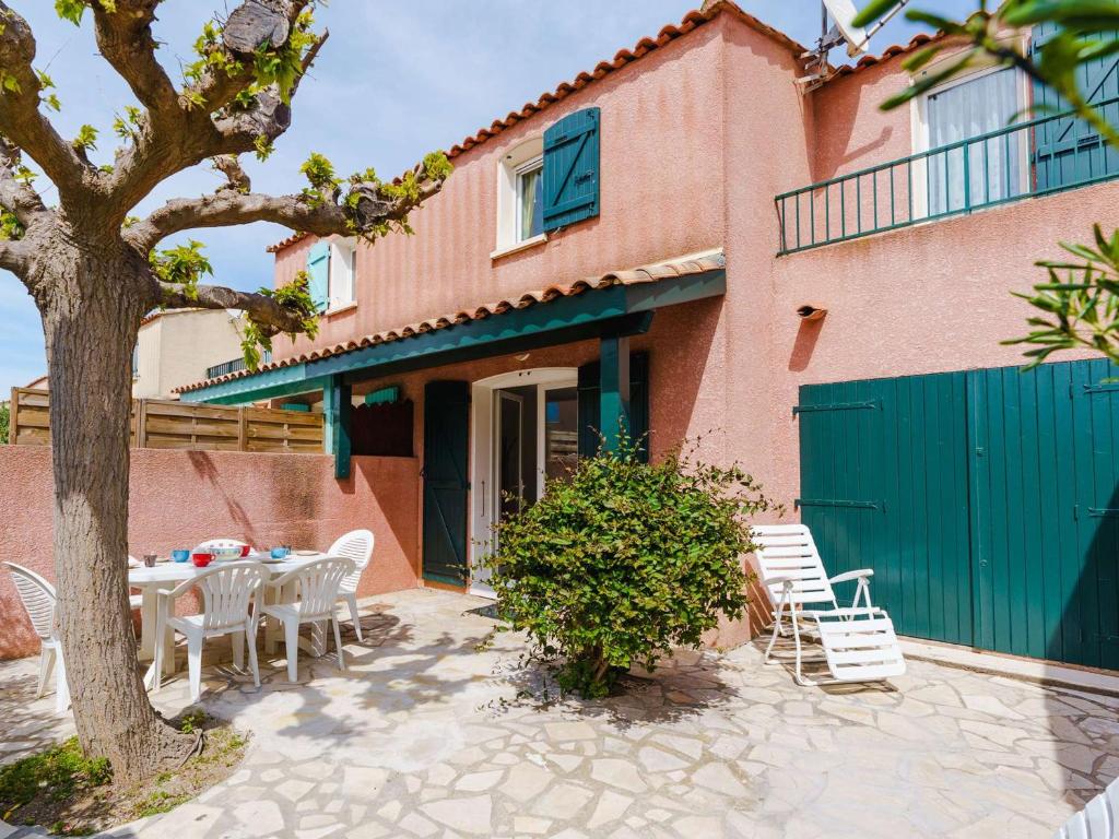 un patio avec une table et des chaises devant une maison dans l'établissement Pavillon 4P, 6 couchages, proche plage, avec WIFI et grande terrasse - Gruissan - FR-1-409-18, à Gruissan