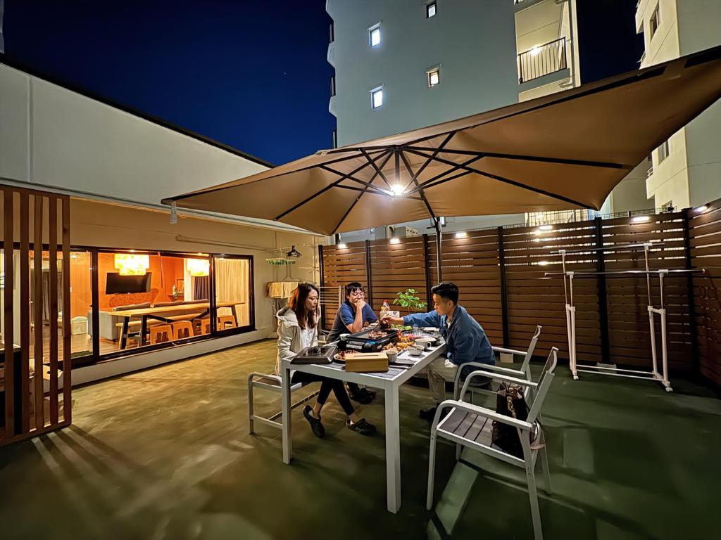 un groupe de personnes assises à une table sur un patio dans l'établissement 桜Inn-通天閣403, à Osaka