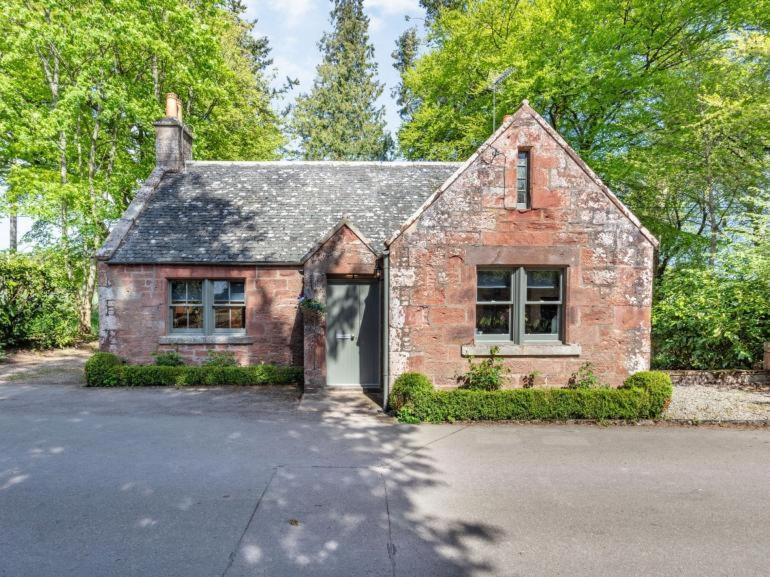 a brick house with a garage in a driveway at Gate Lodge in Fettercairn