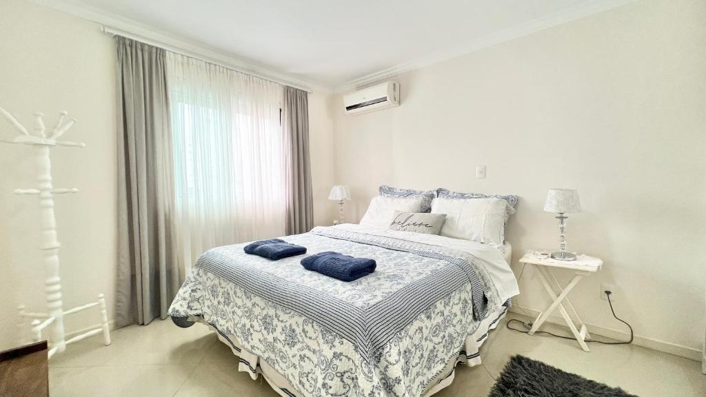 a white bedroom with a bed with blue towels on it at Apto Próximo a Vila Germânica in Blumenau