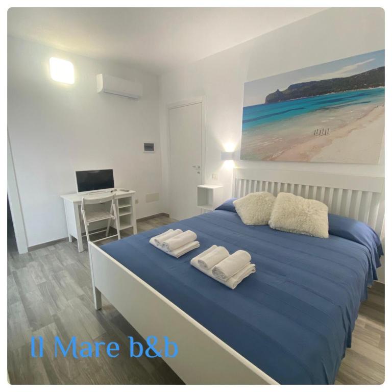 een slaapkamer met een blauw bed en handdoeken bij Il mare b&b in Quartu SantʼElena