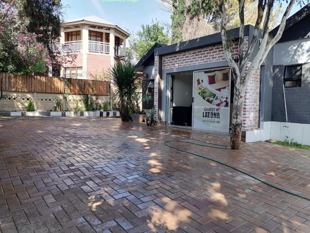 a brick driveway with a tree in front of a garage at Latona Guest House in Johannesburg
