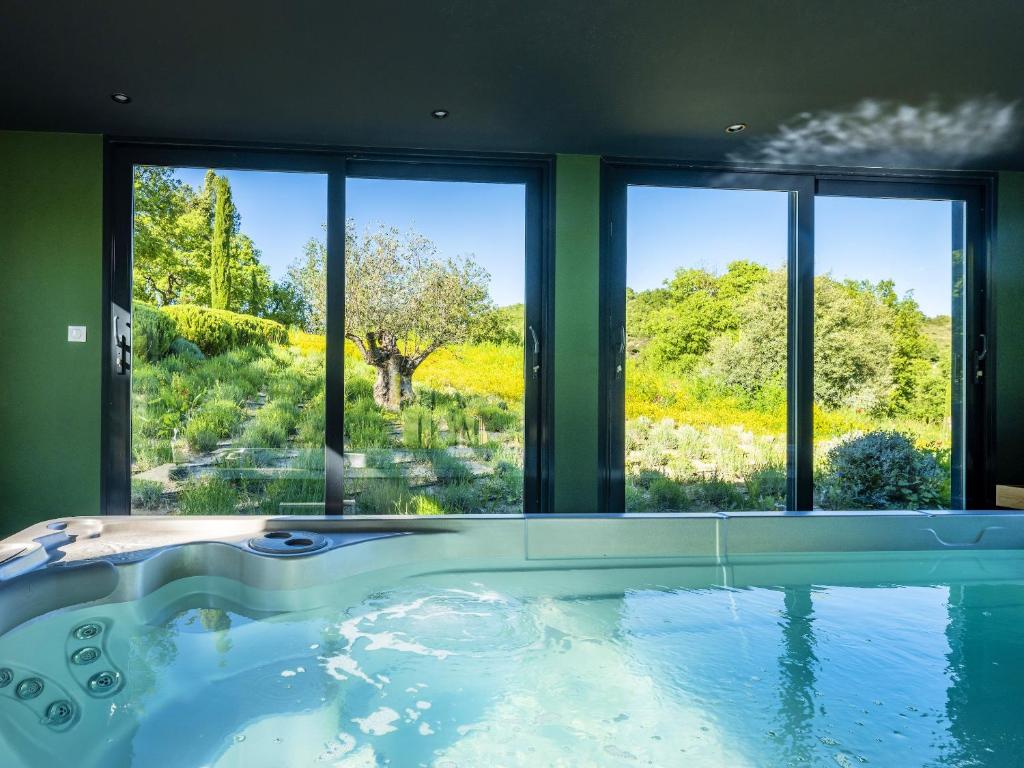 a bathtub with a view of a garden through windows at Studio avec piscine partagee sauna et wifi a Forcalquier in Forcalquier