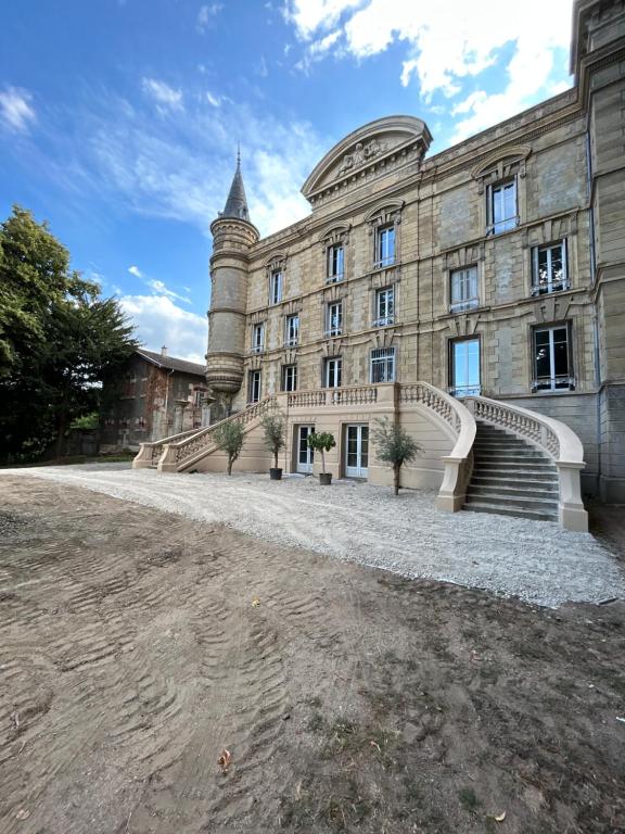 un grand bâtiment en pierre avec des escaliers et une tour dans l'établissement Château Le Fournel, à La Fouillouse