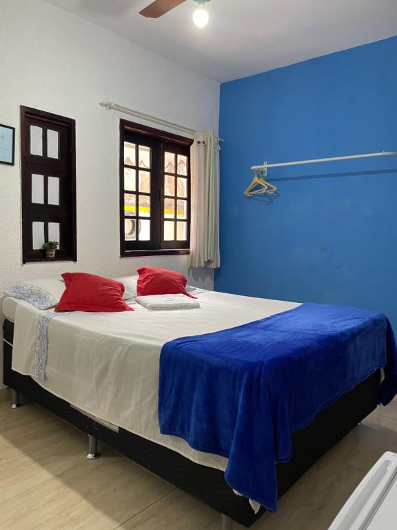 een blauwe slaapkamer met een groot bed met rode kussens bij Quarto com banheiro no térreo in Araruama