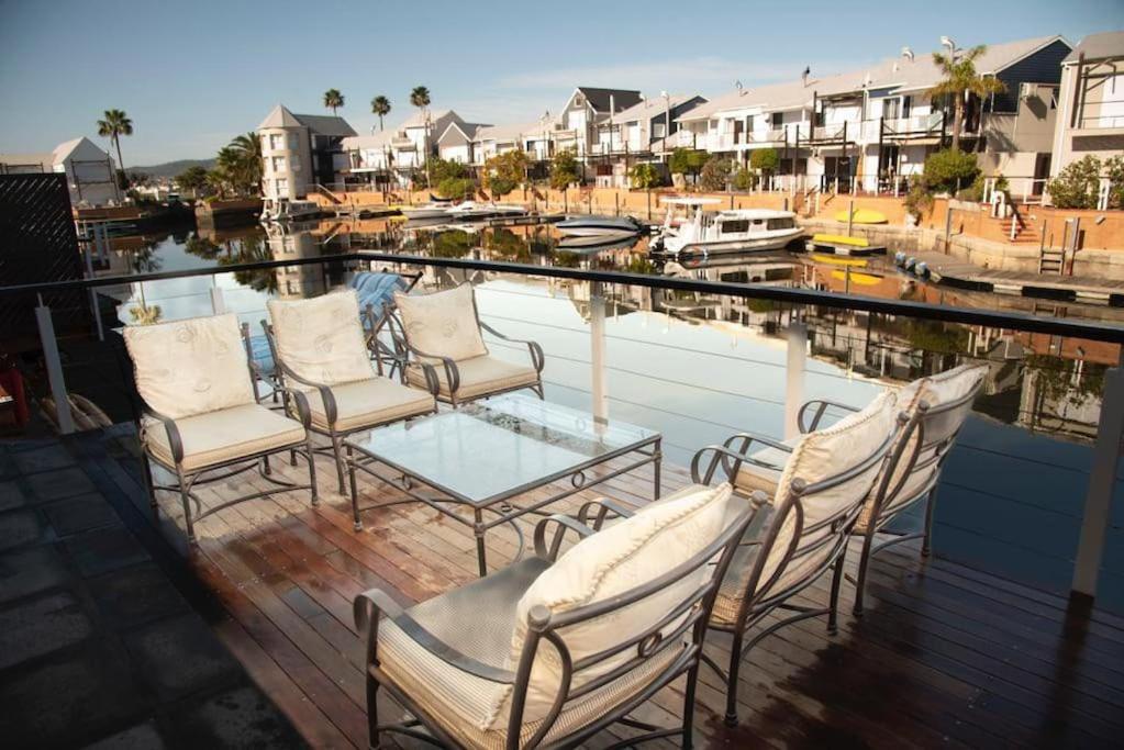 克尼斯納的住宿－Waterfront- C25 Knysna Quays with pool，甲板上的一组椅子和一张玻璃桌