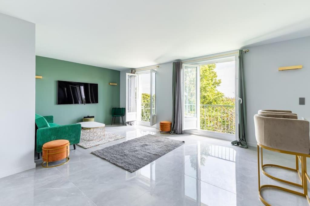 ein Wohnzimmer mit einem Sofa und einem TV in der Unterkunft Magnifique Appartement avec vue sur la Tour Eiffel in Bagneux