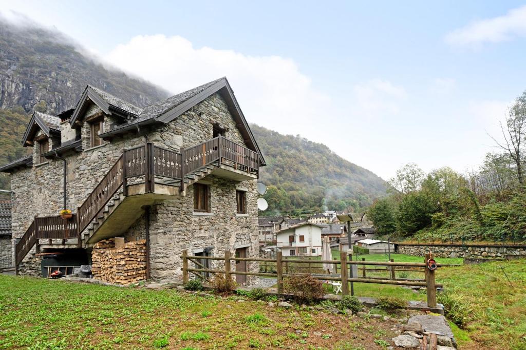 an old stone house with a wooden fence in a field at Titti in Anzino