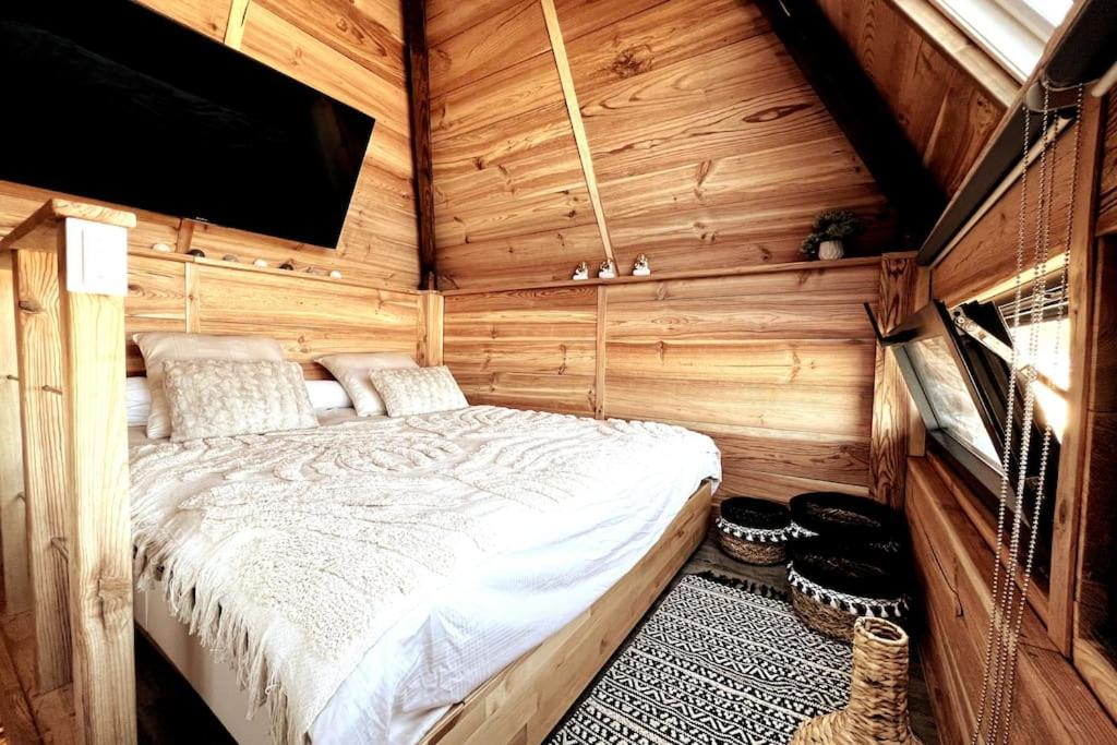 ein Schlafzimmer mit einem Bett in einer Holzhütte in der Unterkunft Chalet et Jaccuzy sur la plage in Biscarrosse