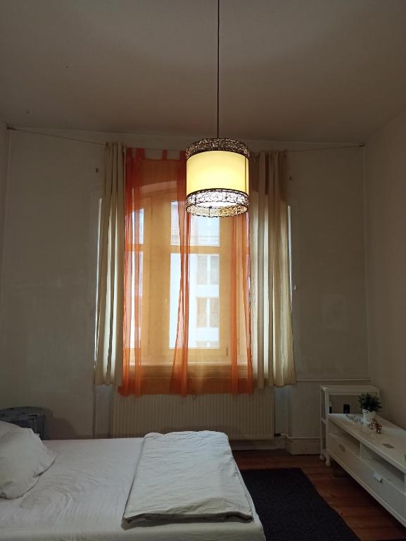 Un dormitorio con una cama y una ventana con una lámpara de araña. en Private room in a shared apartment, free parking en Fulda