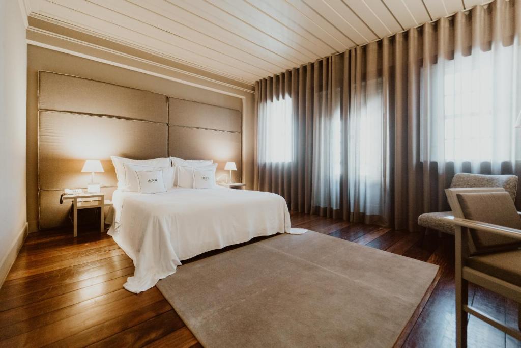 a bedroom with a white bed and a large window at Hotel da Oliveira in Guimarães