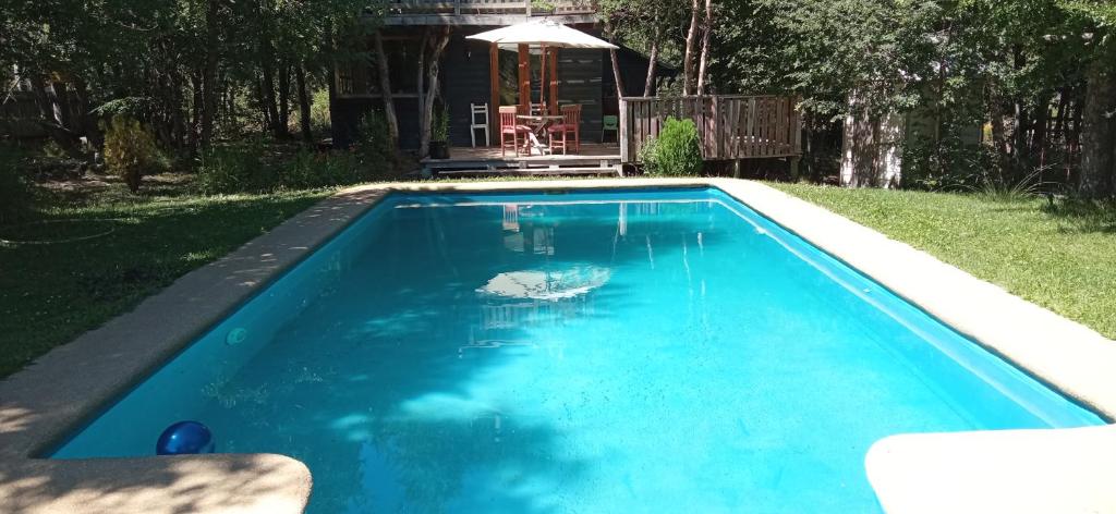 una piscina de agua azul en un patio en CABAÑAS LODGE LOS COIHUES 2 VALLE LAS TRANCAS/TERMAS DE CHILLAN /NEVADOS DE CHILLAN en Pinto