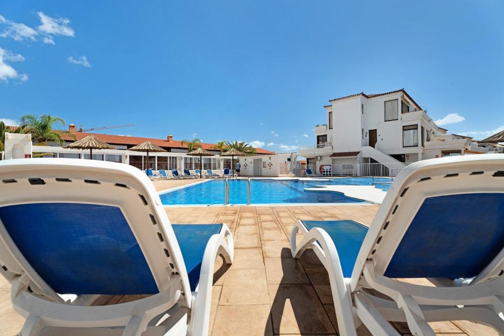 a pair of chairs sitting next to a swimming pool at Blue Dream Pebble Beach in San Miguel de Abona