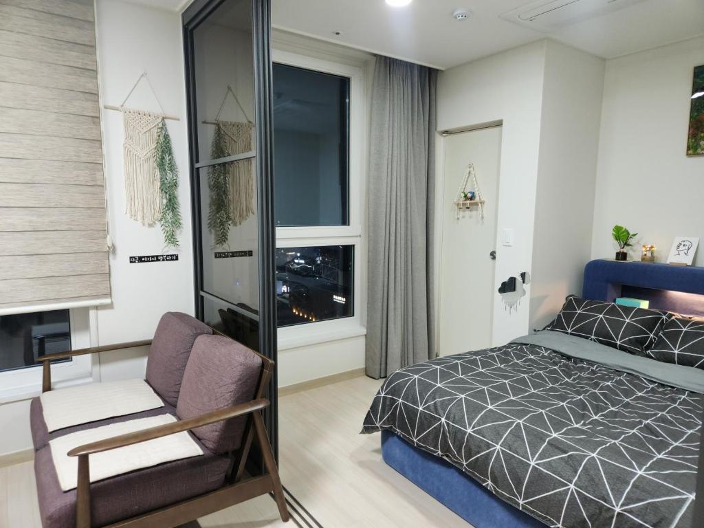 a bedroom with a bed and a chair and a window at The Mark Sokcho Residence Hotel #15F in Sokcho