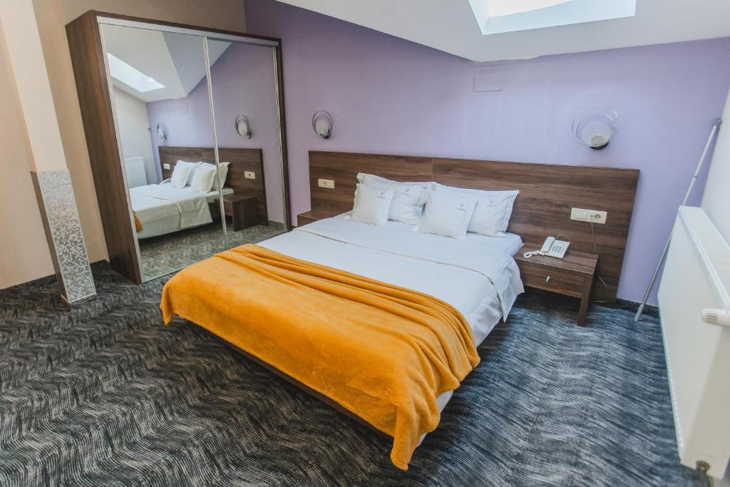 um quarto de hotel com uma cama grande e um espelho em Caro Boutique Hotel em Oradea