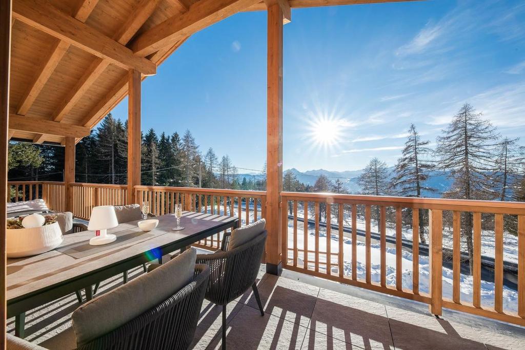 eine Holzterrasse mit einem Tisch und Stühlen auf einer Terrasse in der Unterkunft Piz Aich Natur Chalet Panorama in Avelengo