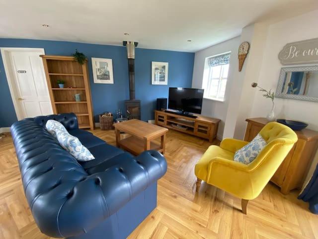 a living room with a blue couch and a yellow chair at Seahorse Cottage in Helston