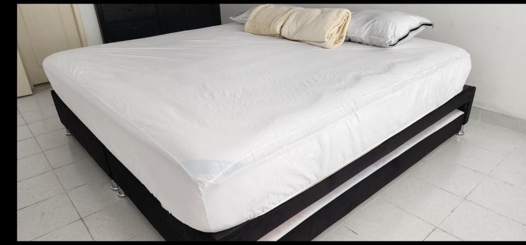 a bed with white sheets and pillows on it at Excelente Apartamento Confortable, Central, Bonito y Económico in El Espinal