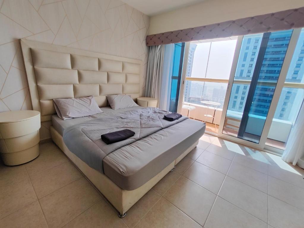 a bedroom with a large bed with a large window at SKY High Stays in Dubai
