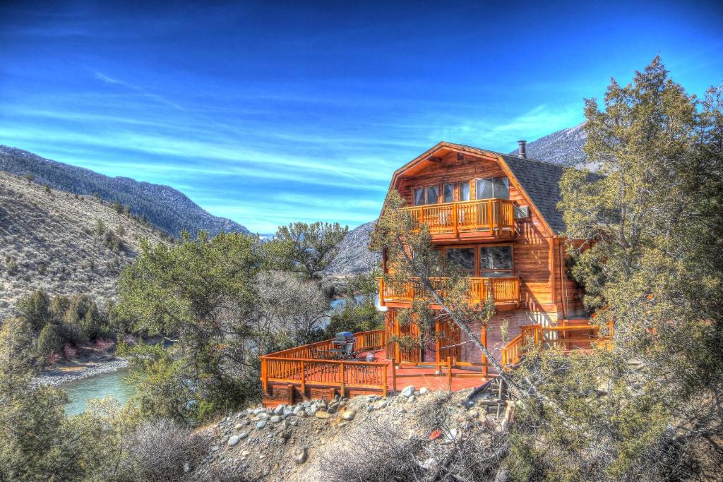 una cabaña de madera en las montañas con un río en Premier Yellowstone River Home en Gardiner