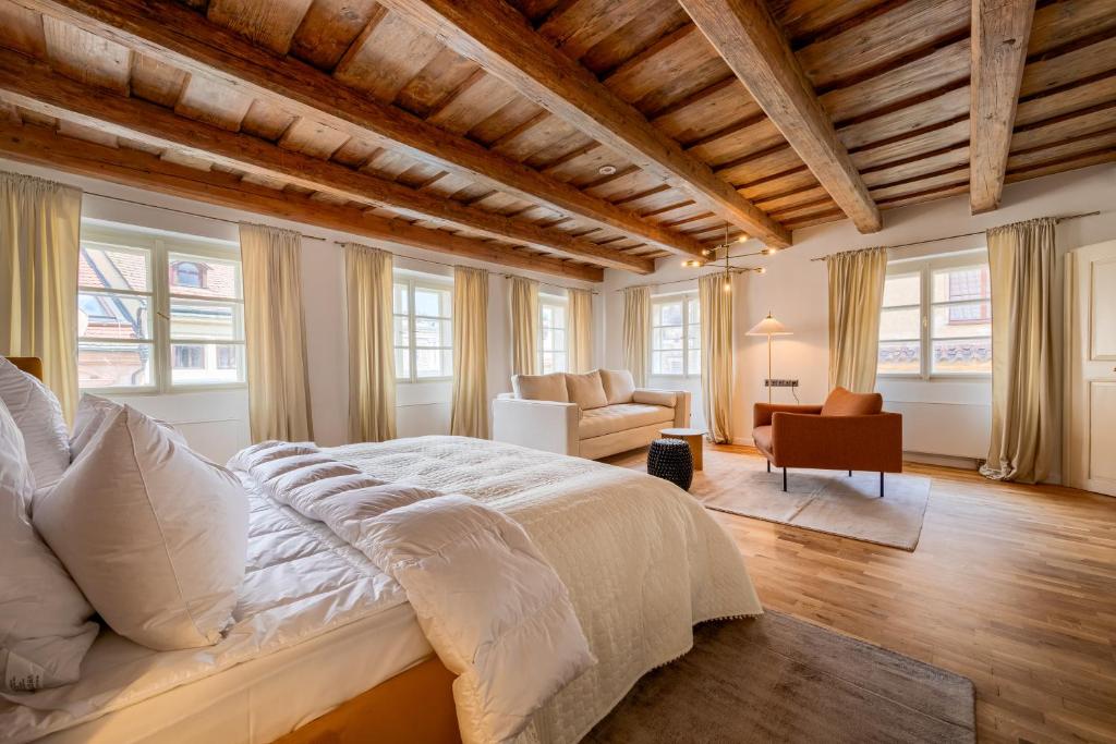a bedroom with a large bed in a room with windows at Domus Balthasar Boutique Hotel in Prague