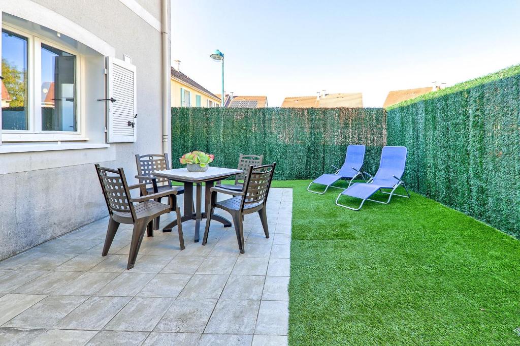 a patio with chairs and a table and grass at Gîte La Vapillone Paris Marne-la-Vallée in Serris