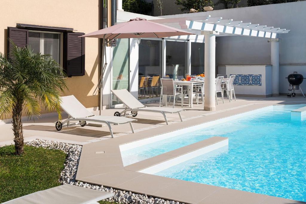 une piscine avec une table, des chaises et un parasol dans l'établissement Villa Giutitta, à Taormine