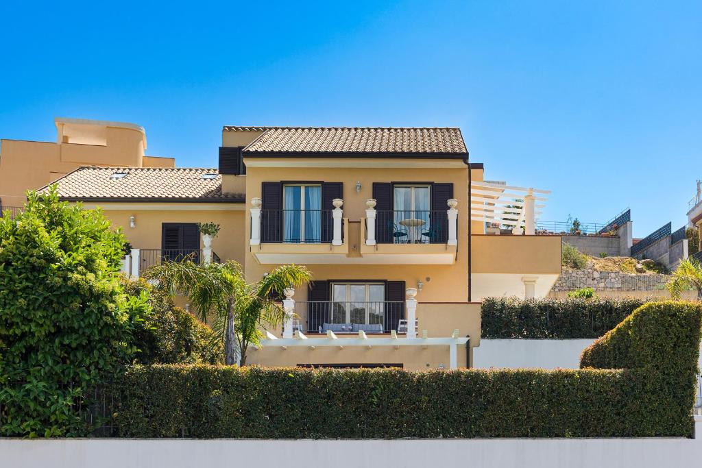 une maison jaune avec des buissons devant dans l'établissement Villa Giutitta, à Taormine